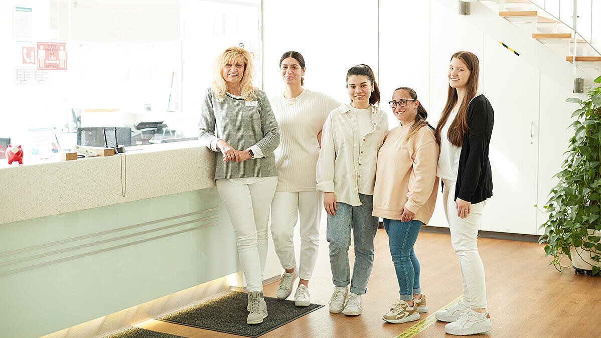 Eine Gruppe von fünf Frauen steht im Flur des Medizinischen Versorgungszentrums für Neurologie und lächelt in die Kamera.