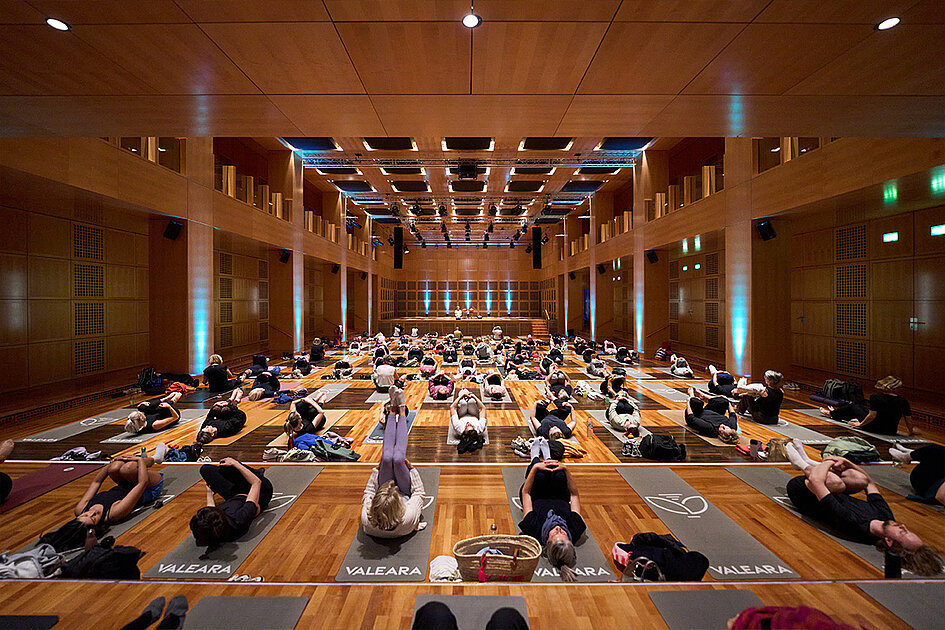  Eine Blick in den Robert-Schumann-Saal, auf dem Boden sind Frauen die Yoga machen.