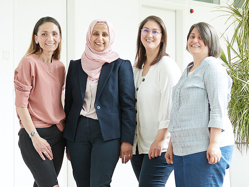 Eine Gruppe von vier Frauen steht im Flur des Medizinischen Versorgungszentrums für Allgemeinmedizin und lächelt in die Kamera.