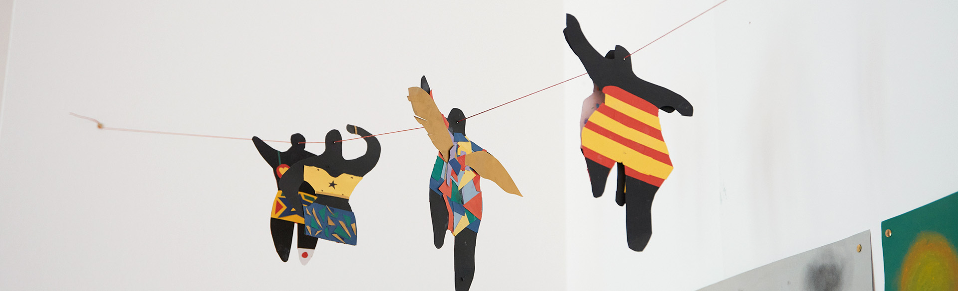 Papierfiguren hängen an einem Nylonfaden in der Luft.