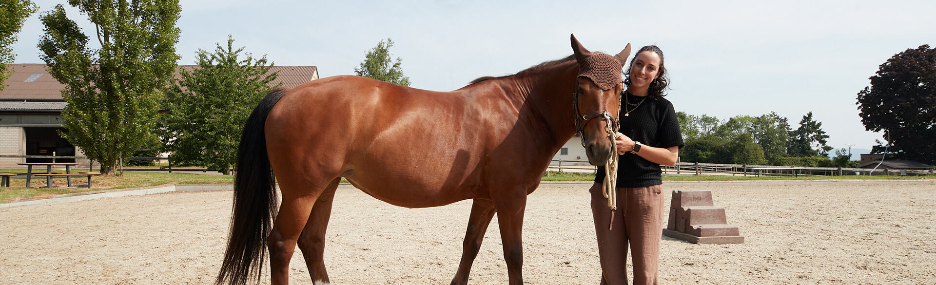 Eine Reittherapeutin steht mit einem Pferd auf einer Koppel in Bad Neuenahr.