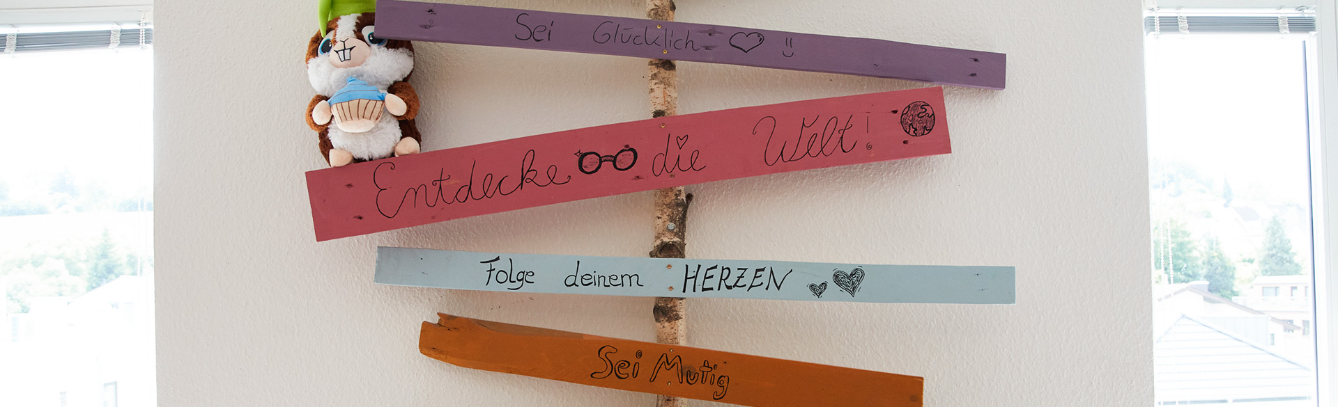 Bunte Schilder mit Sprüchen hängen an einer Wand der Psychiatrische Institutsambulanz Daun 