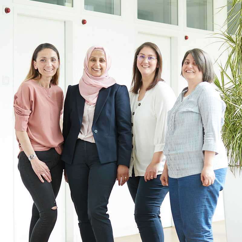 Eine Gruppe von vier Frauen steht im Flur des Medizinischen Versorgungszentrums für Allgemeinmedizin und lächelt in die Kamera.