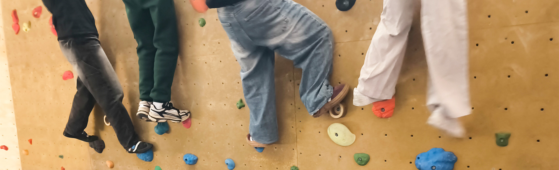 Ansicht auf 4 kletternde Kinder an einer Kletterwand