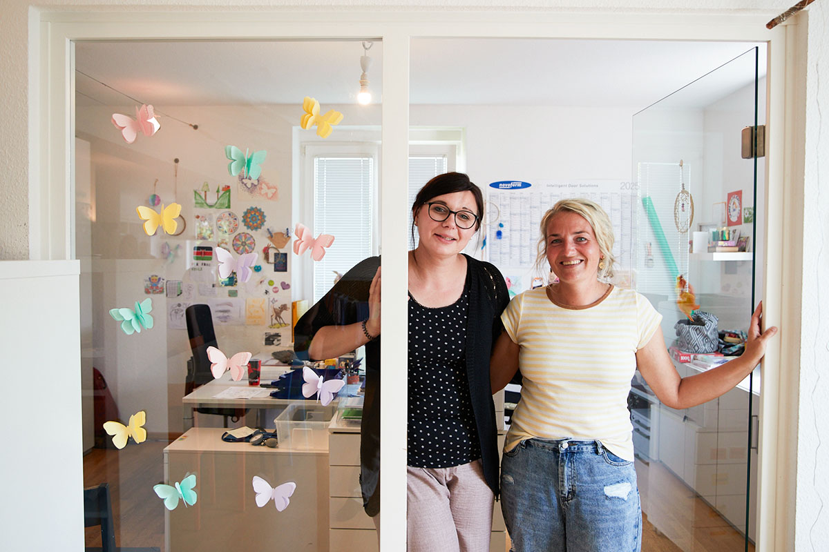 Zwei Frauen stehen in der Tagesklinik in Daun und lächeln in die Kamera.