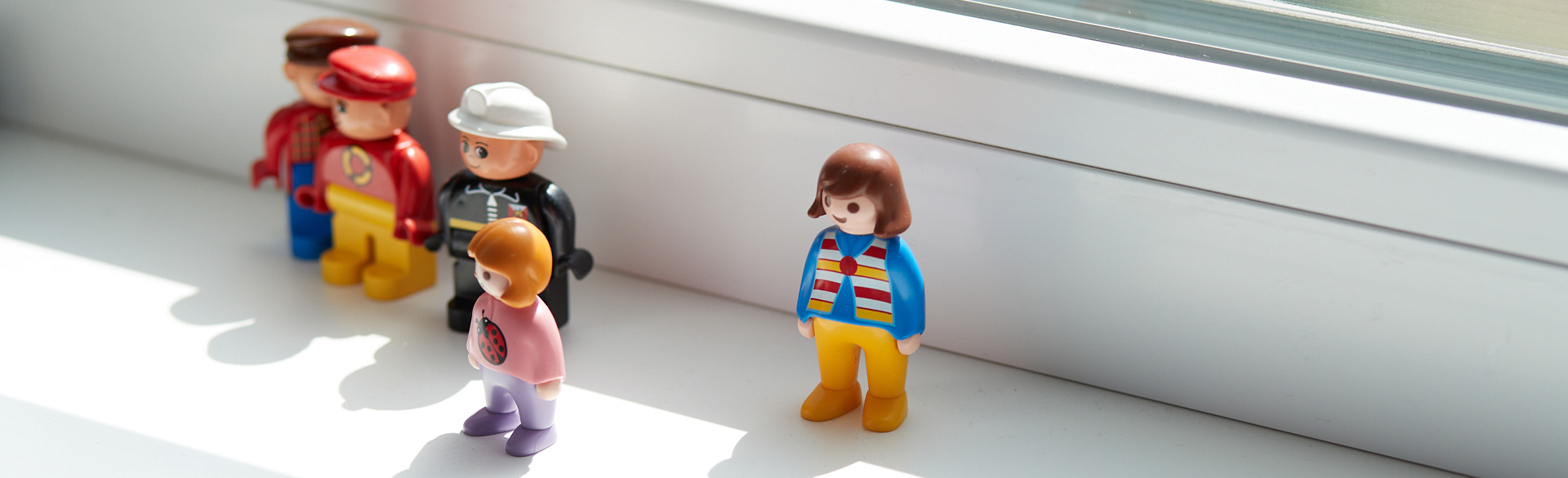 4 Playmobi-Figuren stehen auf einer Fensterbank.